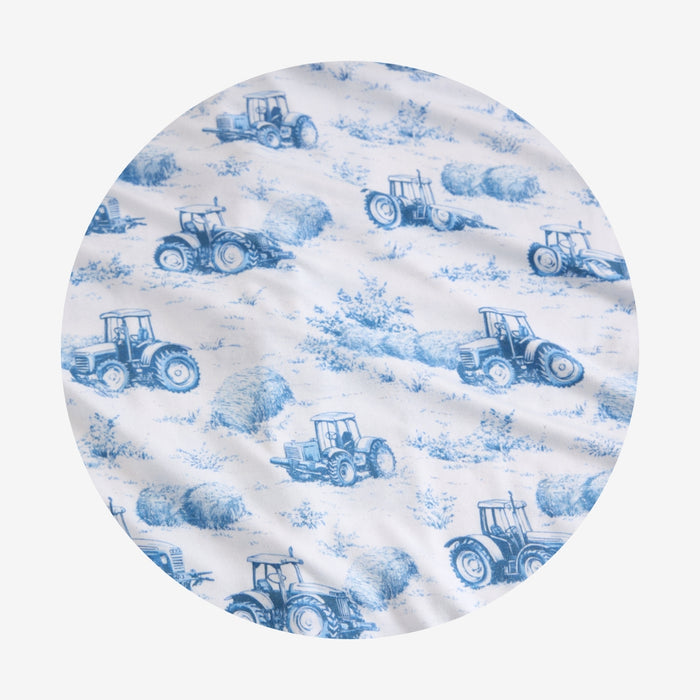 Round fabric swatch with blue tractor and hay pattern on a white background