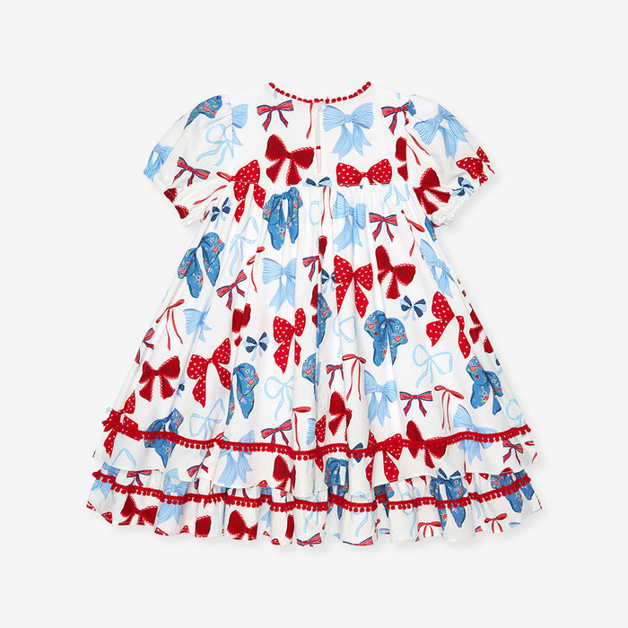 Children's dress with red, blue, and white bow pattern on a white background