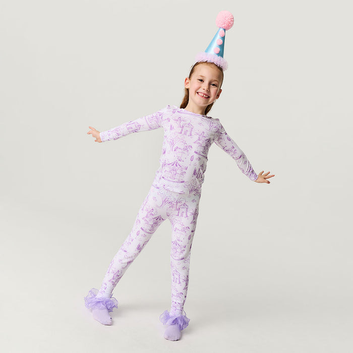 Child wearing a purple pajama set with a party hat on a light gray background
