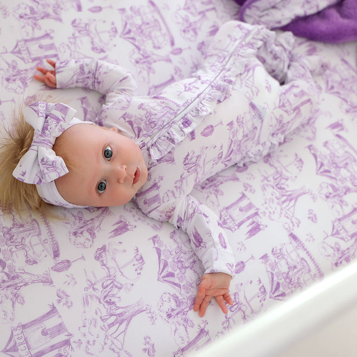 Baby lying on a purple and white patterned blanket