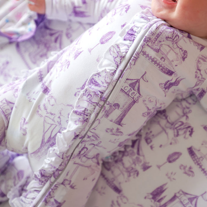 Close-up of a baby in a purple and white patterned outfit with a zipper.