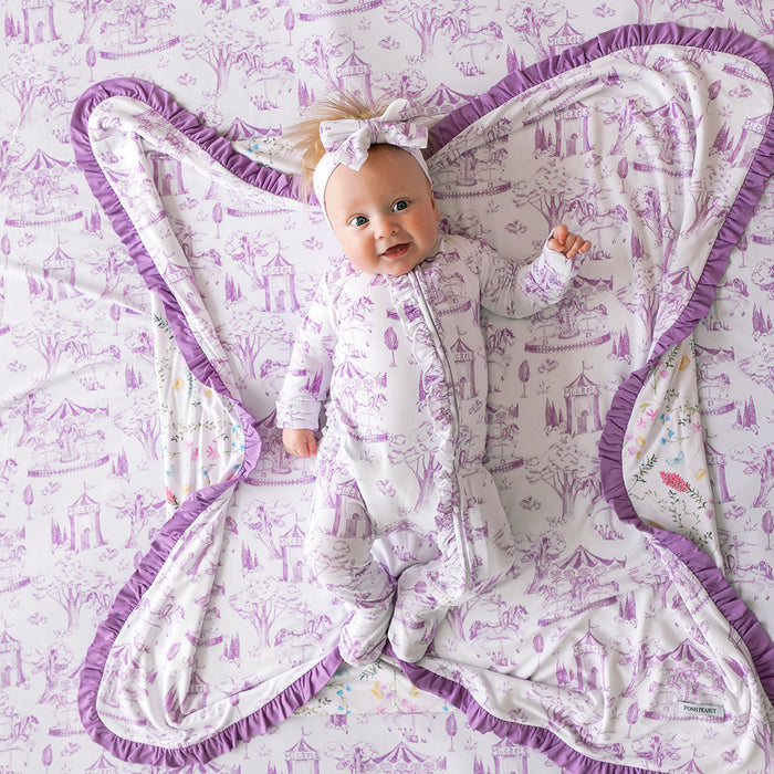 Baby lying on a purple and white patterned blanket with a matching outfit.