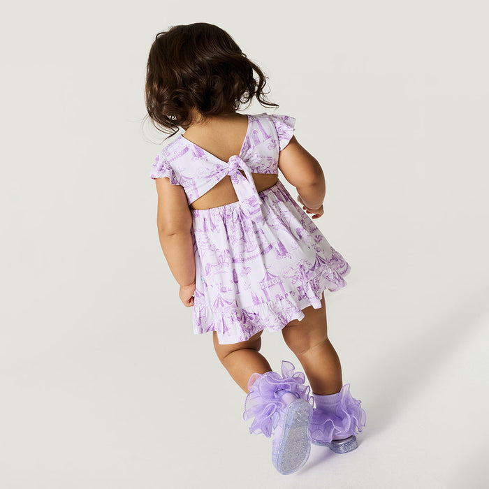 Child wearing a purple floral dress with cut-out back and matching shoes on a white background