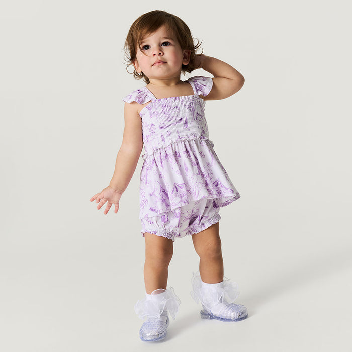 Child wearing a purple floral dress on a plain background