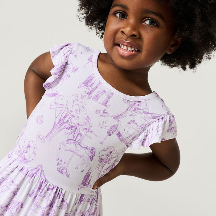 Child wearing a white dress with purple floral patterns against a plain background