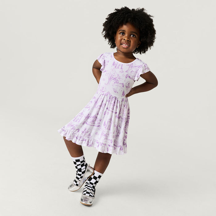 Young girl wearing a light purple floral dress on a plain background