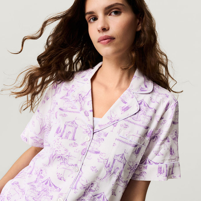 Woman wearing a purple and white patterned pajama set against a plain background