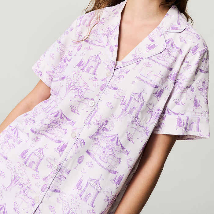 Person wearing a purple and white patterned shirt on a plain background