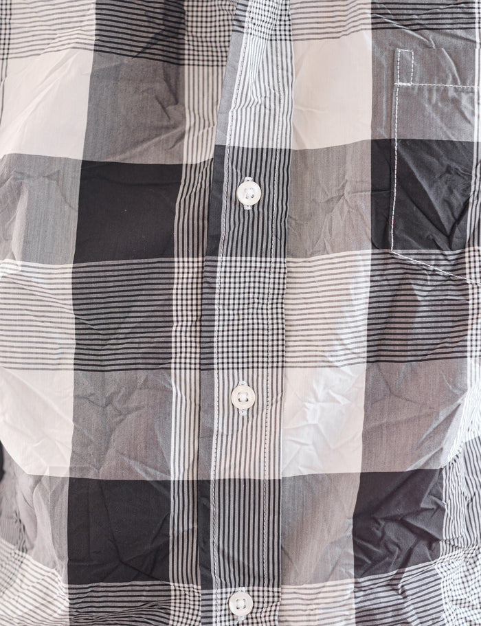 A close-up of a plaid button-up shirt in black, white, and gray, showing the fabric texture and pattern details.