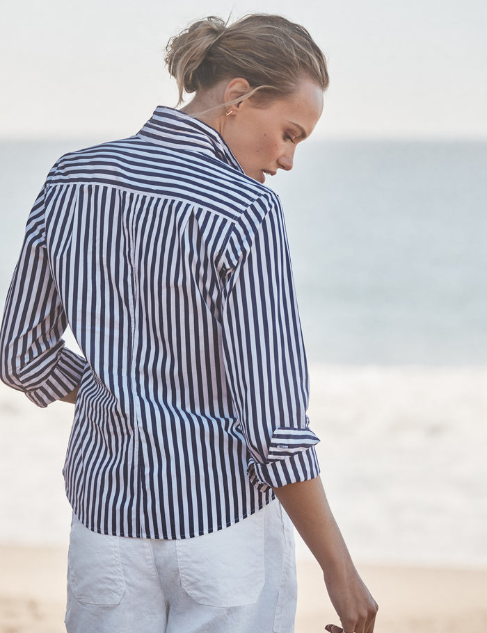 Woman wearing a navy and white striped shirt on a beach