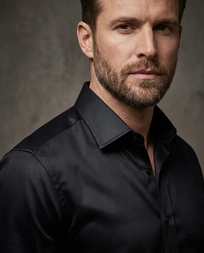 Man wearing a black dress shirt against a gray background