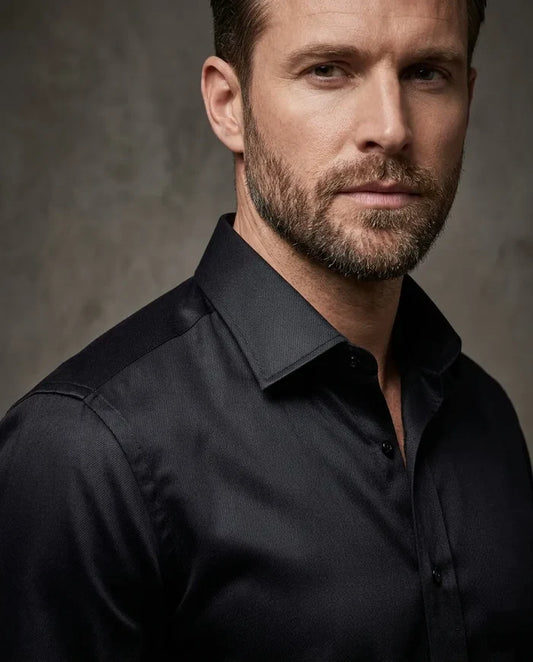 Man wearing a black dress shirt against a gray background