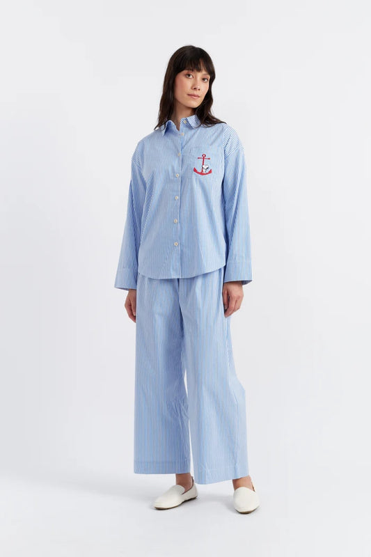 Woman wearing a light blue pajama set with an anchor emblem on a white background