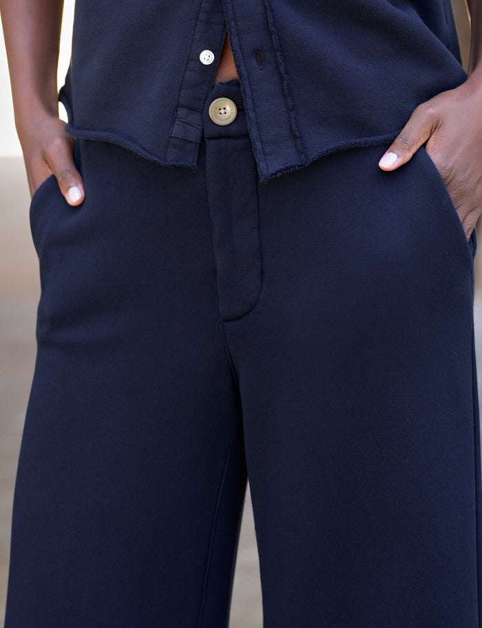 Close-up of a person wearing dark navy wide-leg trousers with hands in the pockets, paired with a matching navy top.