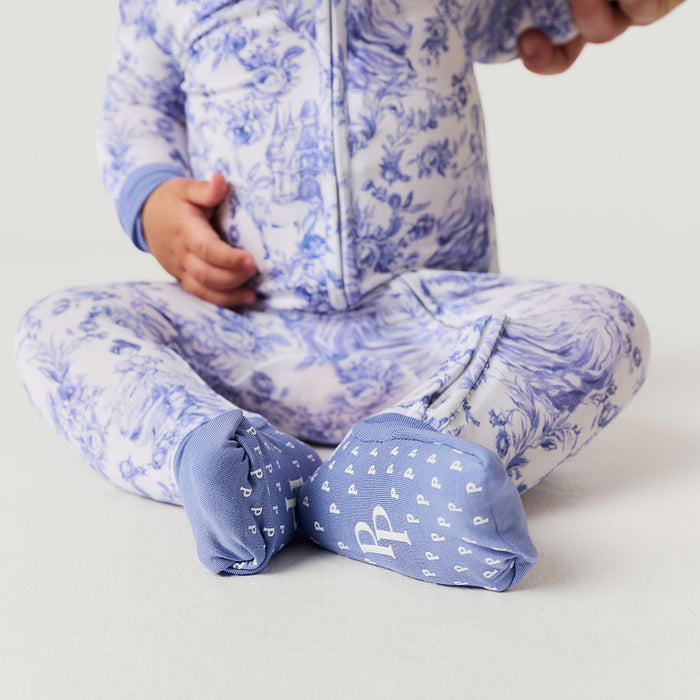 Child wearing a blue and white patterned one piece with matching socks on a light gray background