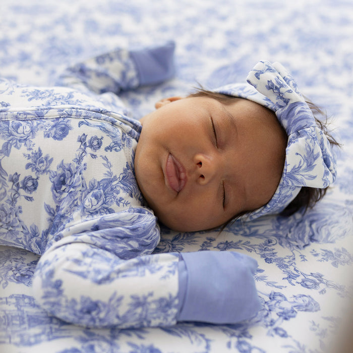 Close-up of baby wearing blue floral one piece lying on a matching blanket
