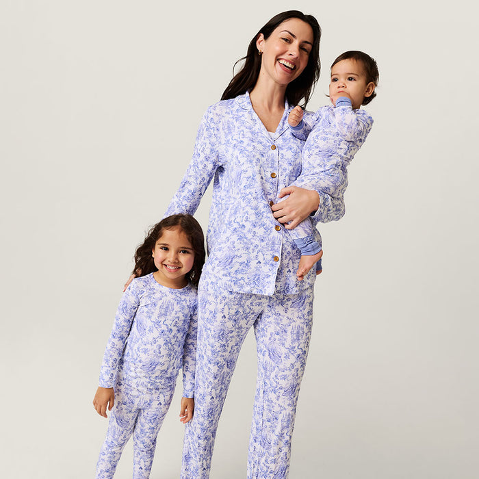 Woman and two children wearing matching blue floral pajamas against a plain background