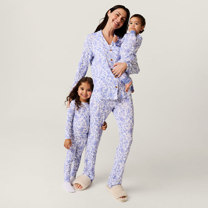 Woman and two children wearing matching blue floral pajamas on a plain background