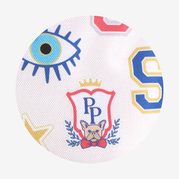 Decorative pillow with eye design, crest, and dog illustration on a white background