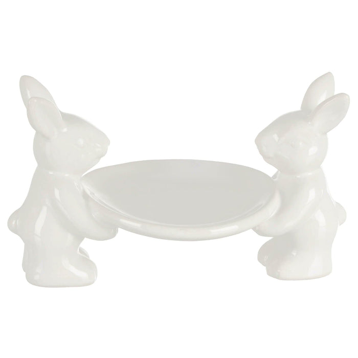 White ceramic cake plate with two rabbit figures on a white background