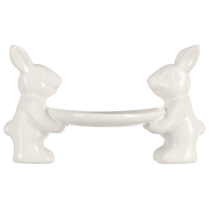 2 white Easter rabbits holding a cake plate on a white background