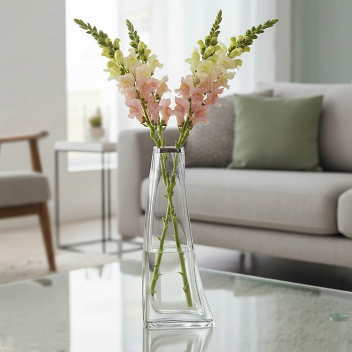 Clear glass vase filled with snapdragon flowers on a glass table in a living room