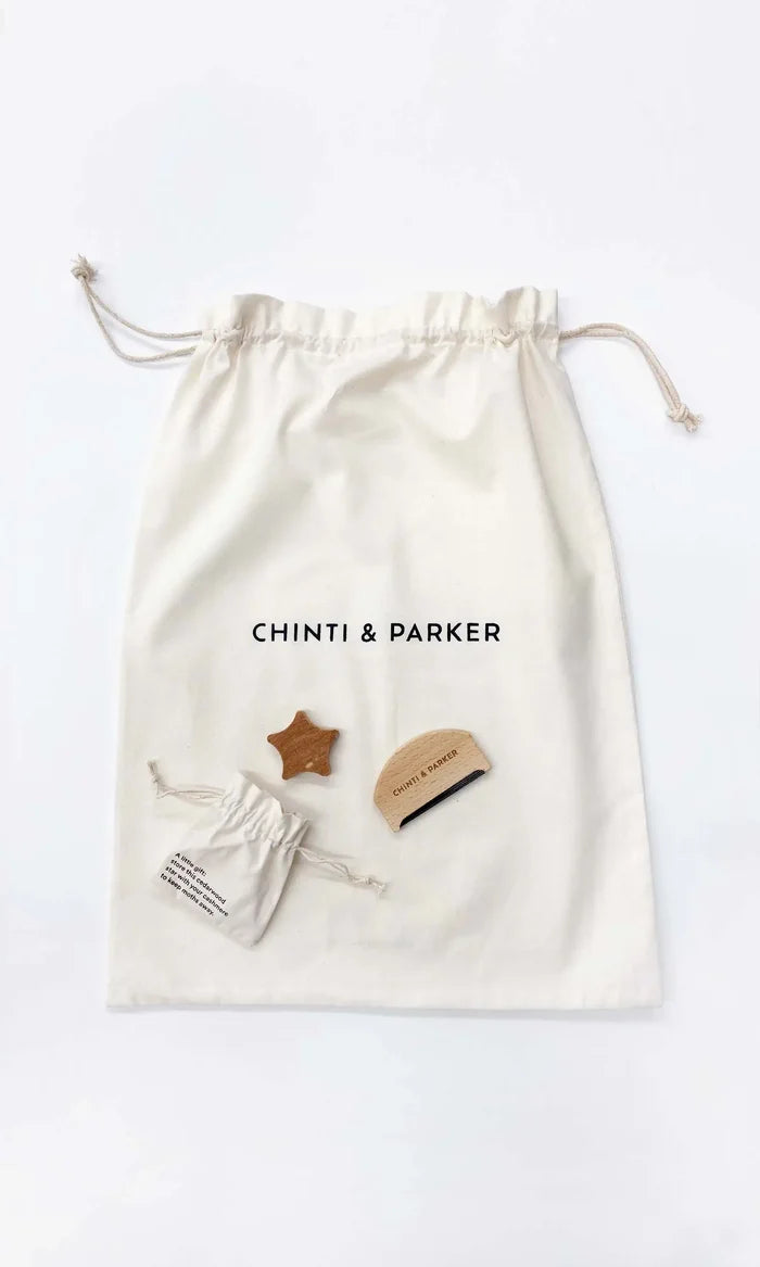 Drawstring bag with 'Chinti & Parker' branding containing small items on a white background