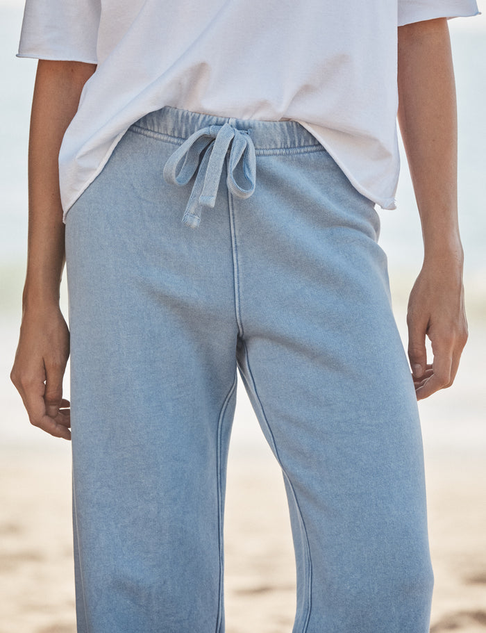 Light blue sweatpants worn by a person on a beach.