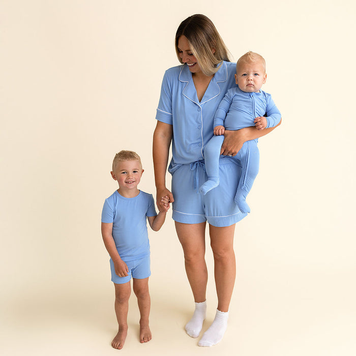 A parent and two children standing together in matching Posh Peanut Chatham Blue pajama sets.