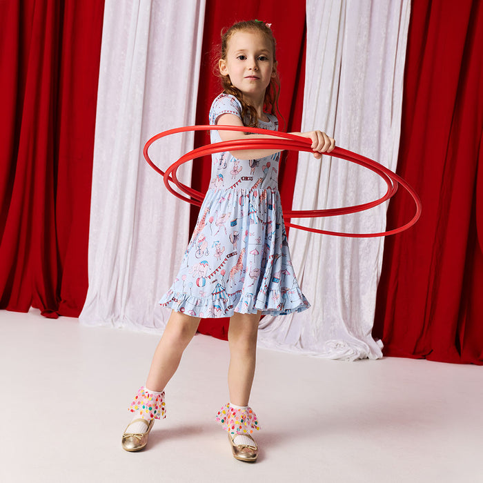 Young girl holding a red hula hoop in front of red and white curtains