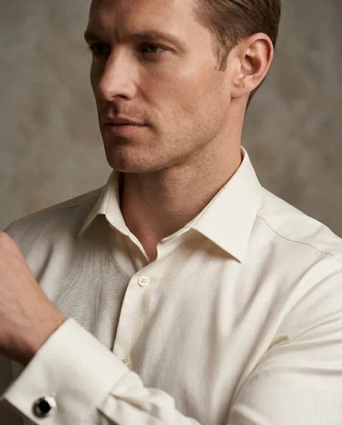 Man wearing a light-colored dress shirt against a neutral background
