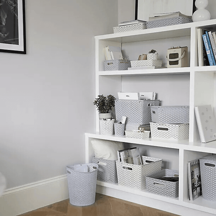 waste paper basket bin in office space with paper inside in front of shelves with curver storage baskets and bins