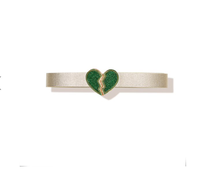 Introducing the "Don't Go Breaking My Heart Belt - Green": a beige leather belt showcasing a daring statement piece—a striking green heart-shaped buckle adorned with a jagged crack down the middle. The clean white backdrop accentuates its simple yet elegant design, ensuring it stands out as an exceptional accessory.