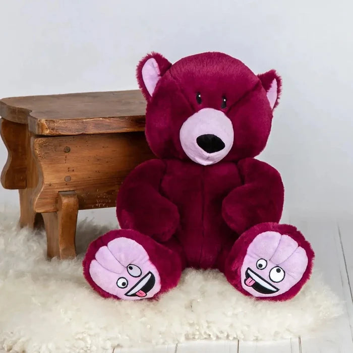 Purple Silly Mood Bear sitting on a rug beside a wooden stool