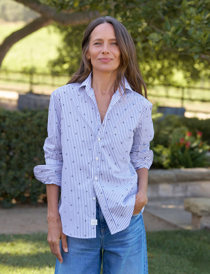 Woman wearing a blue and white striped shirt with rolled-up sleeves outdoors.