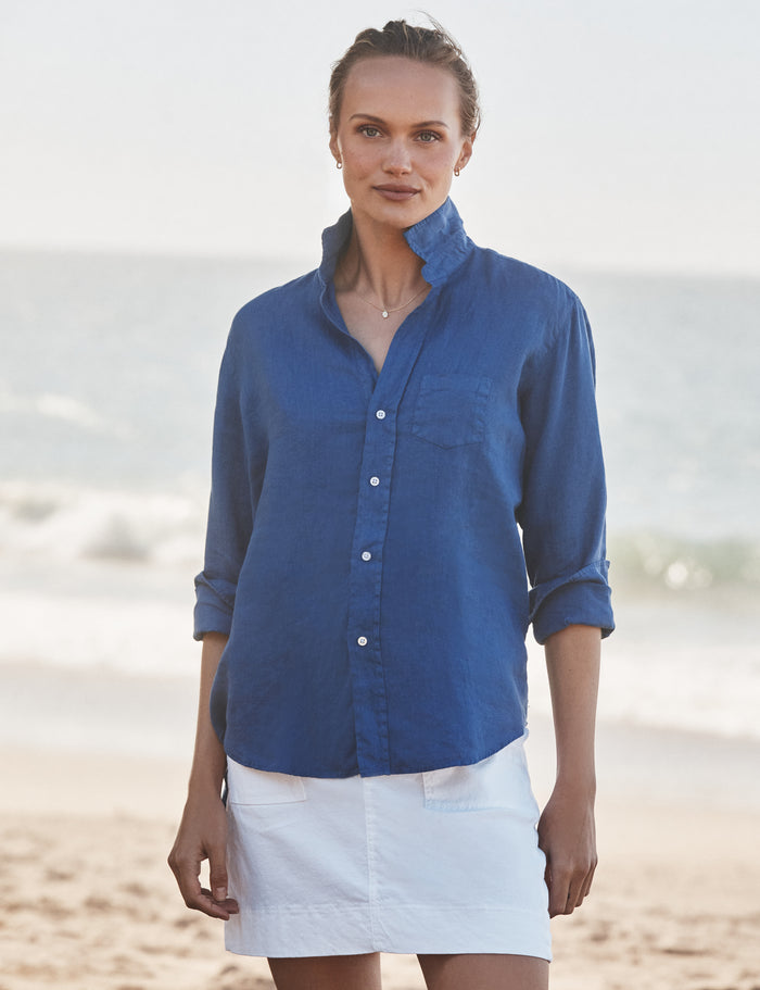 Woman wearing a blue shirt and white skirt on a beach
