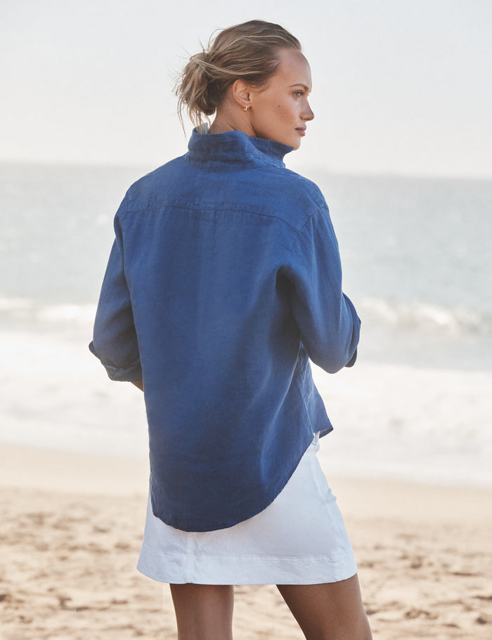 Woman wearing a blue shirt and white skirt on a beach
