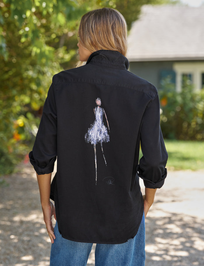Person wearing a black shirt with a white graphic on the back, standing outdoors.