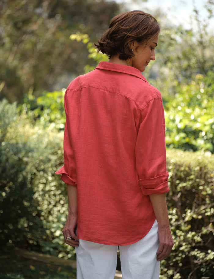 Person wearing a red shirt and white pants standing in a garden