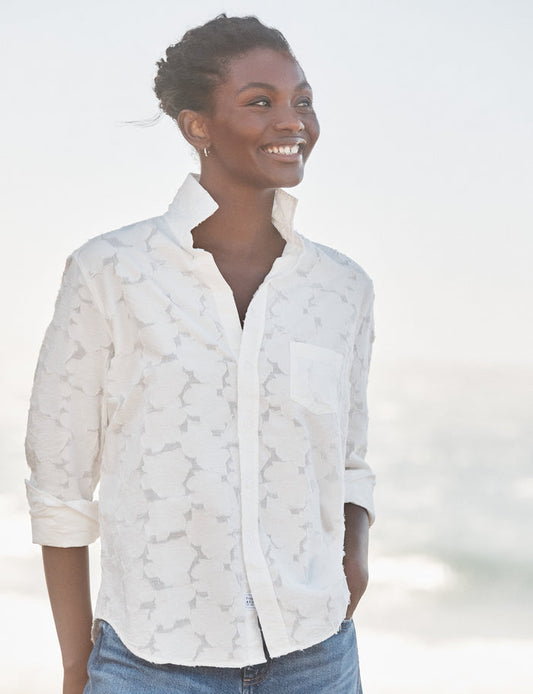 Woman wearing a white patterned shirt with a blurred background