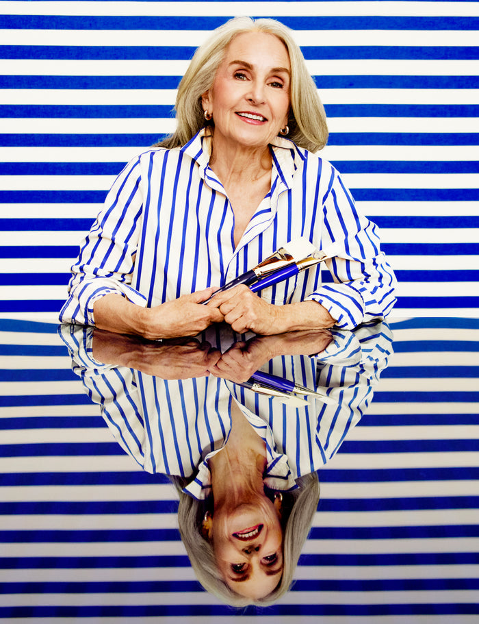Woman in a striped shirt holding books against a blue and white striped background