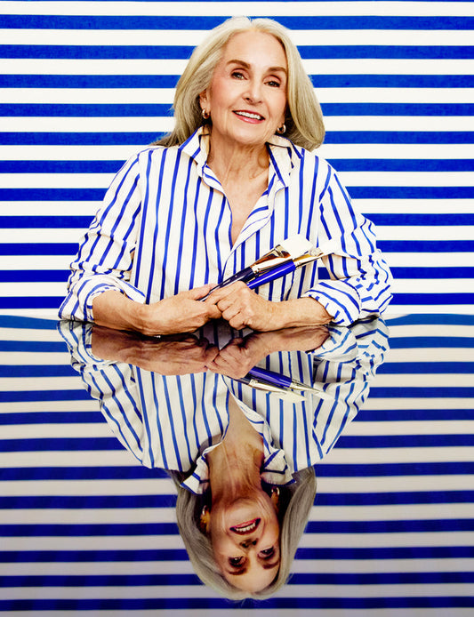 Woman in a striped shirt holding books against a blue and white striped background