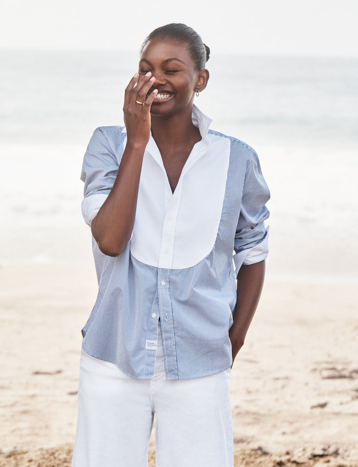 Woman wearing a light blue and white striped shirt on a beach
