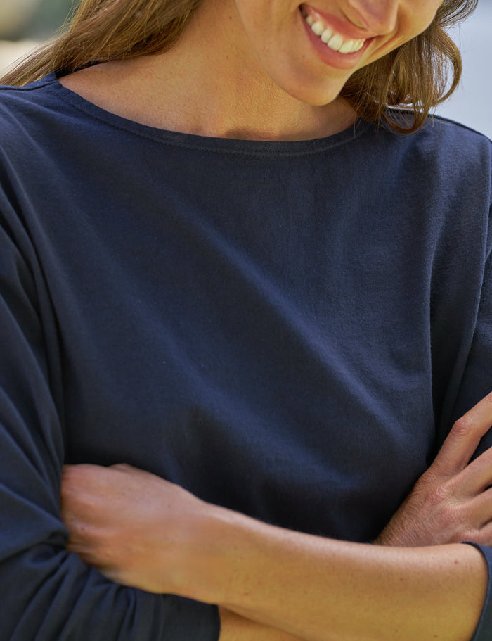 Person wearing a navy blue shirt with arms crossed