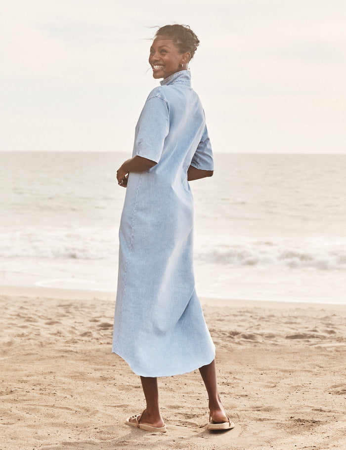Woman wearing a light blue dress standing on a beach.
