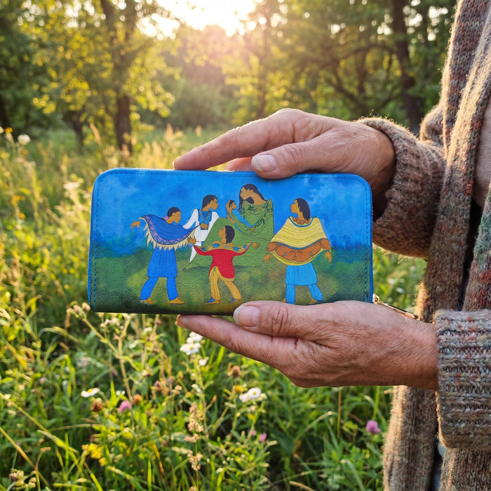 Hand holding a colorful wallet with painted designs of people against a natural background