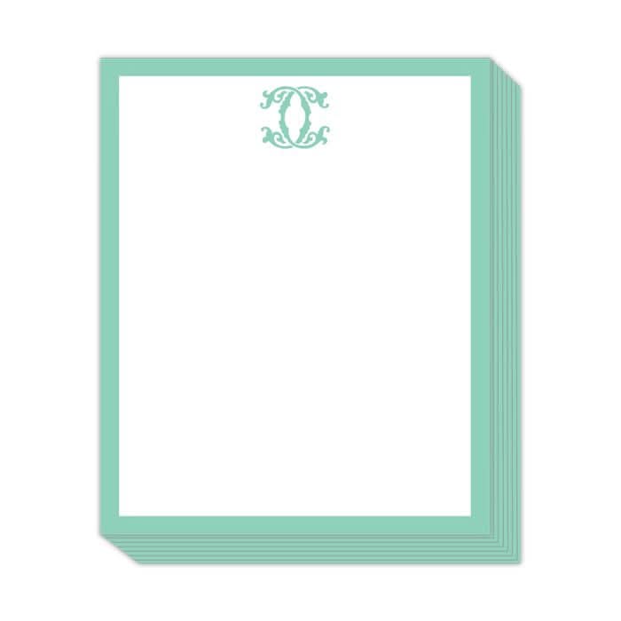The Gift Bar - Short Stack Pad includes 5.25 x 6.5" sheets made of text weight paper, offering blank, white stationery highlighted by a teal border. Each page features an ornate teal monogram or decorative design centered at the top, adding an elegant touch to your correspondence.