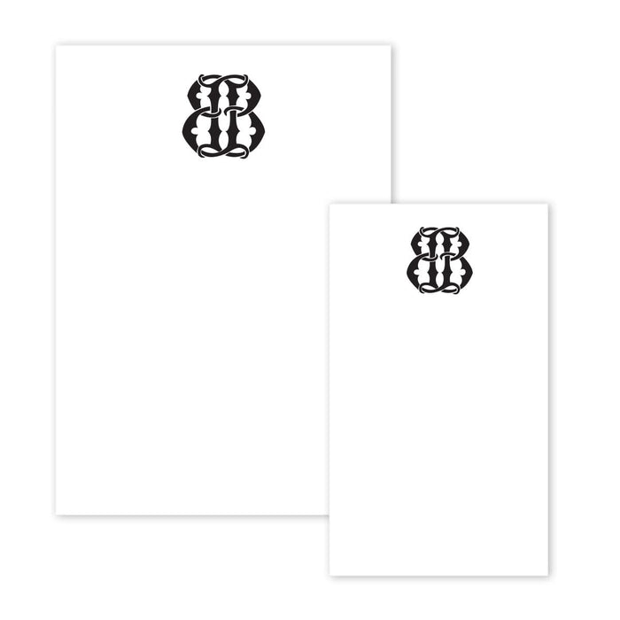 The Gift Bar Notepad Set includes two white sheets, each adorned with an intricate black design resembling abstract shapes or stylized lettering at the top center. The smaller sheet is slightly overlapping the larger one.