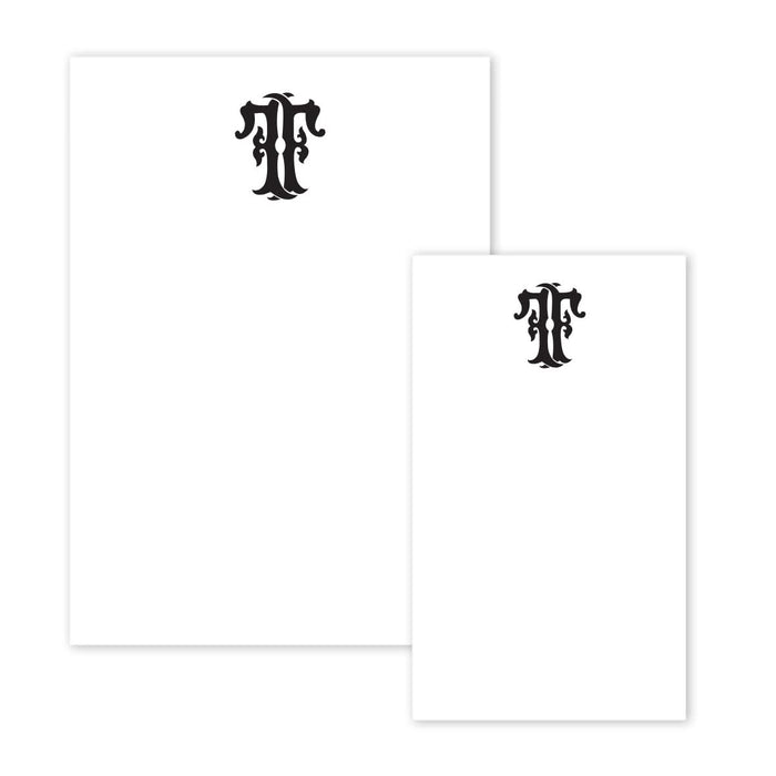 The Gift Bar Notepad Set includes two white notepads with ornate black letter T emblems at the top center. One pad is larger than the other, and the elegant, minimal design beautifully highlights the intricate lettering.
