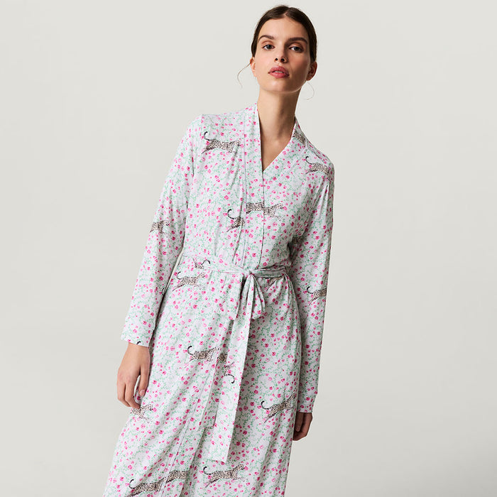 Woman wearing a floral robe with a belt on a plain background
